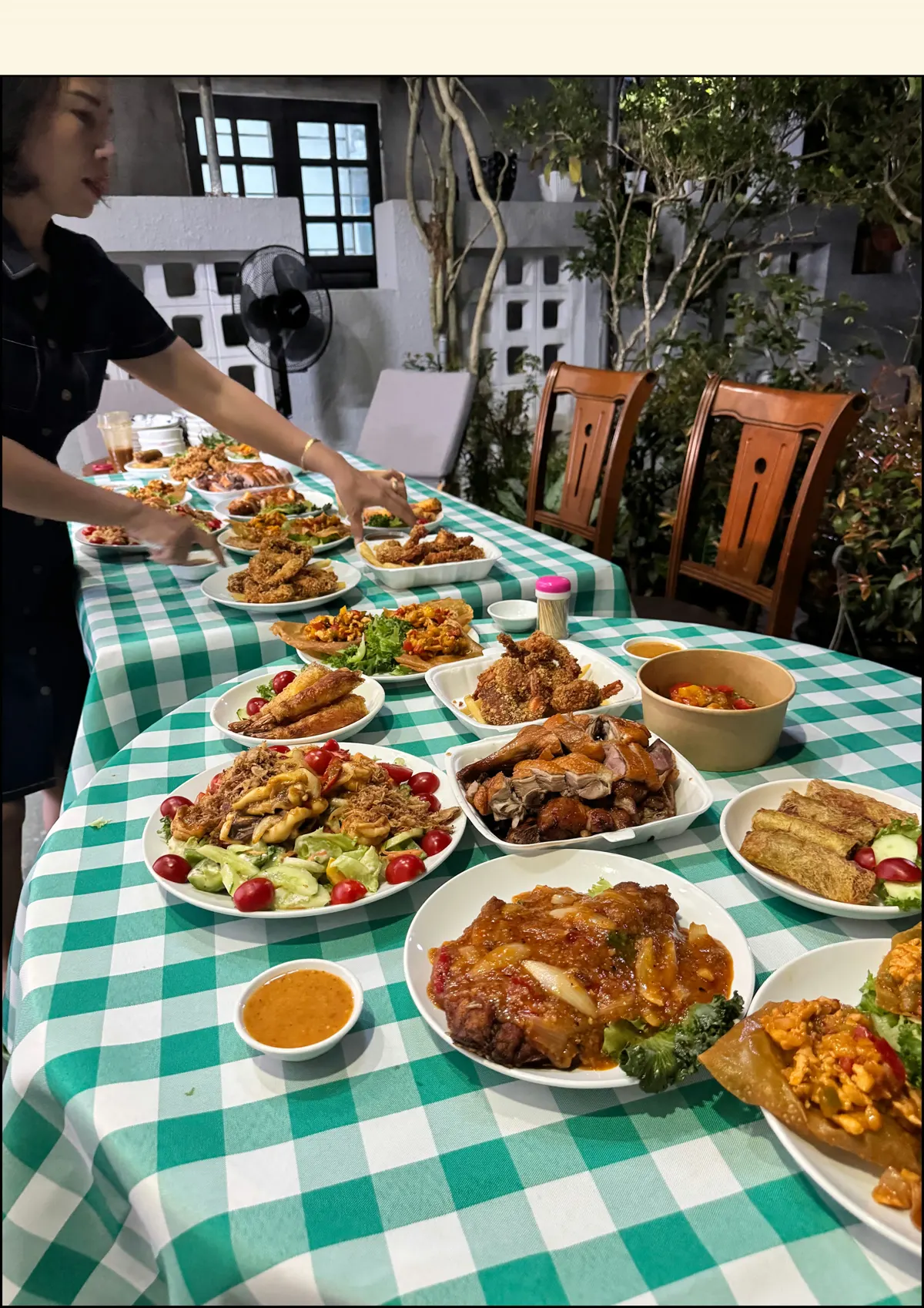 A long table on green gingham cloth laid with plates of Vietnamese dishes